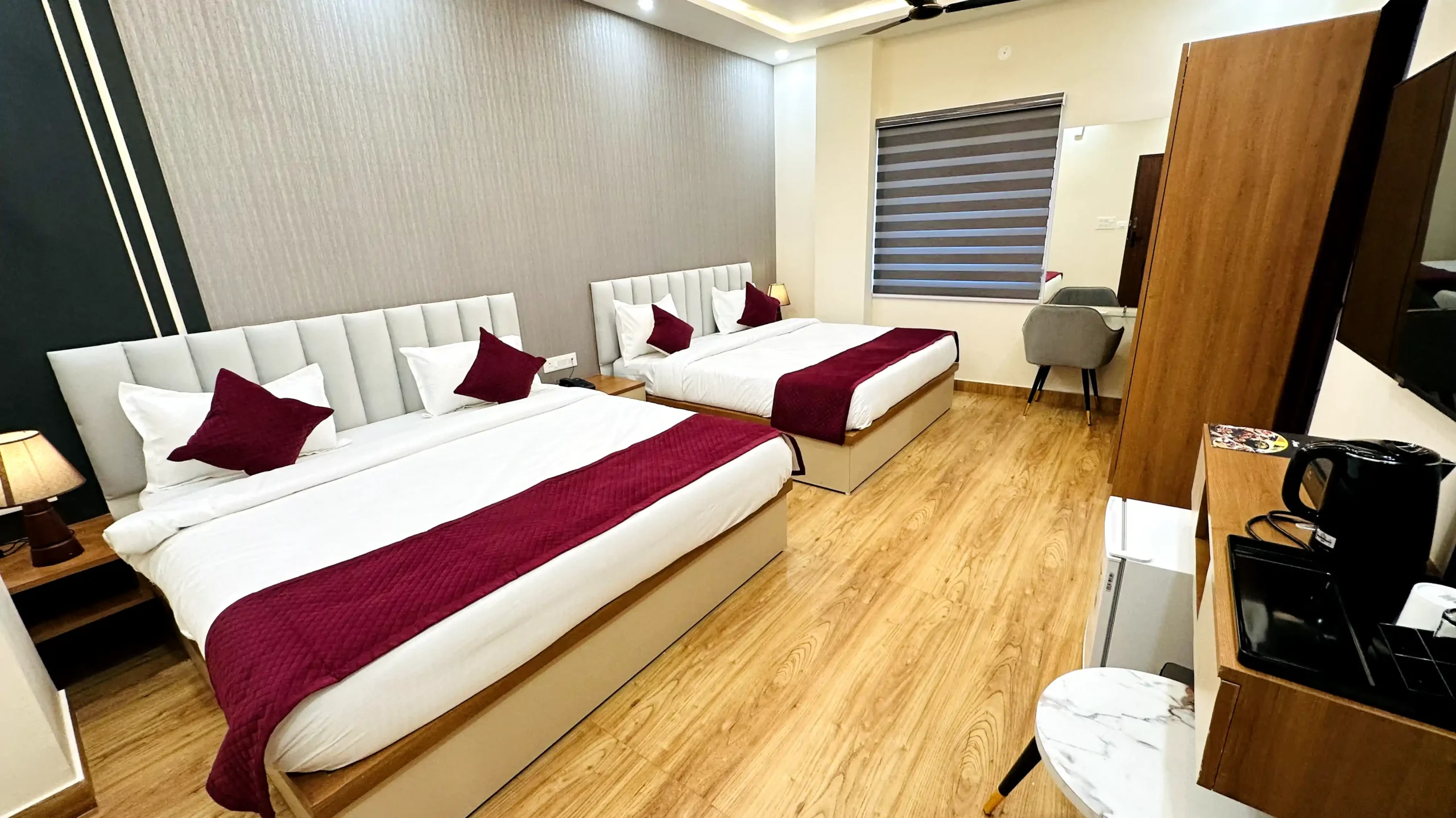 Spacious premium room at The Ummed Jodhpur, featuring a large double bed, elegant wooden furniture, traditional decor accents, and a window with a view of the garden or courtyard.